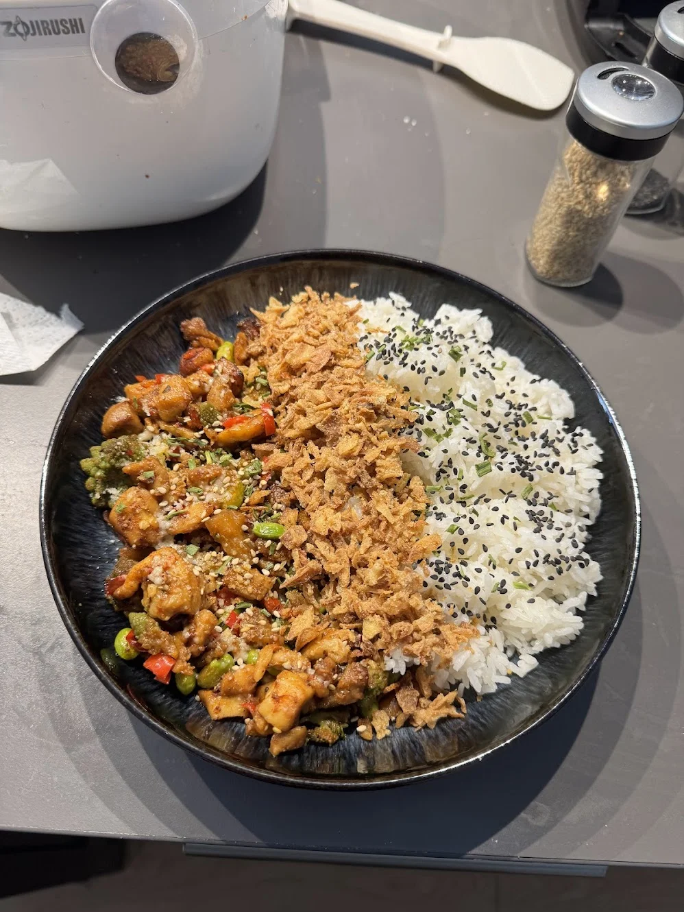 Chicken with mixed vegetables beside jasmine rice, with a line of fried onions between them.